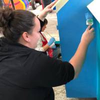 woman paints side of parade float
